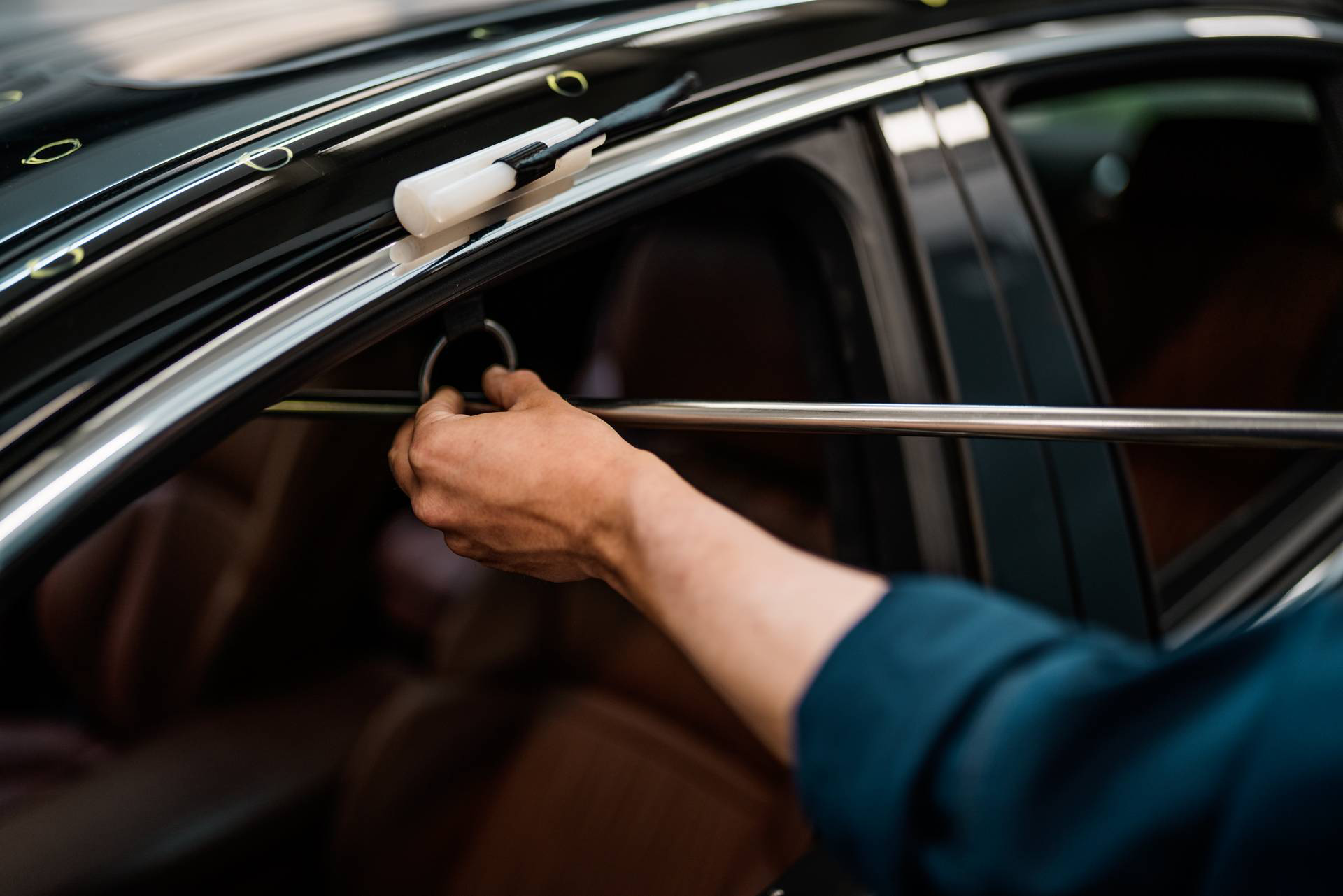 Techniker repariert Hagelschaden am Auto von innen mit Spezialwerkzeug in Werkstatt in Wien