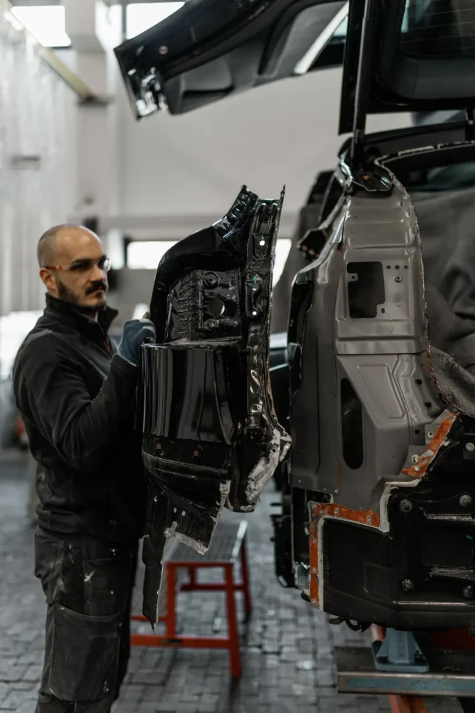 Mechaniker montiert ein Karosserieteil am Heck eines Fahrzeugs während der Instandsetzung