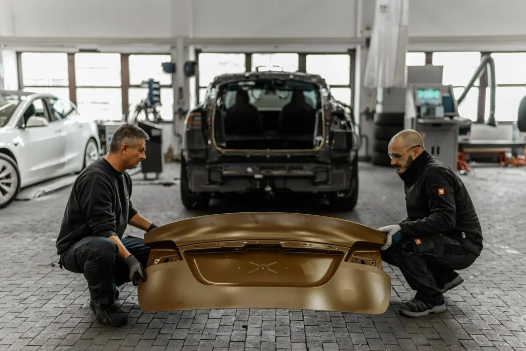 Zwei Mechaniker montieren einen Stoßfänger im Rahmen einer Karosserie- und Unfallreparatur